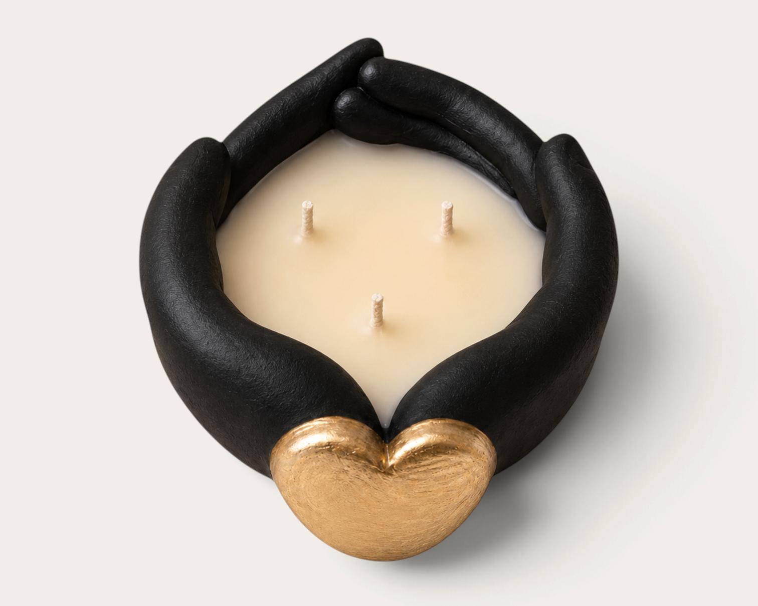 Vela artesanal THE IBIZA CANDLES Black Tuxedo con forma de manos negras sosteniendo un corazón dorado y tres mechas.