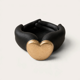 Vela escultórica Black Tuxedo de THE IBIZA CANDLES con forma de manos negras entrelazadas y corazón dorado central.
