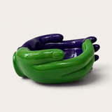 Vela escultórica THE IBIZA CANDLES con forma de manos entrelazadas en colores verde y morado brillante