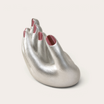 Vela artesanal Pearl de THE IBIZA CANDLES con forma de mano plateada y uñas pintadas de color rojo brillante.