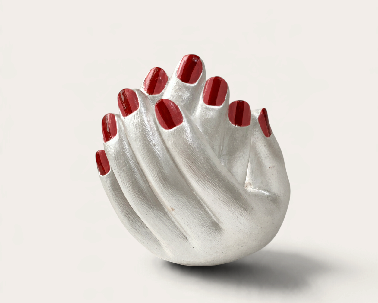 Vela artesanal Pearl de THE IBIZA CANDLES con forma de manos entrelazadas en color plata y uñas pintadas de rojo.