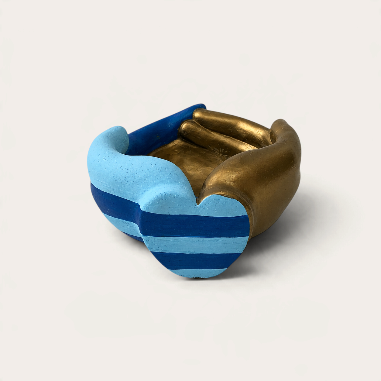 Vela escultórica Gold Mariner de THE IBIZA CANDLES con forma de manos entrelazadas en tonos azul, celeste y dorado.