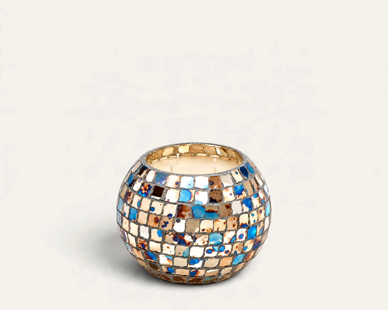 Vela aromática Hippie de THE IBIZA CANDLES en recipiente esférico de mosaico multicolor con tonos azules y dorados.