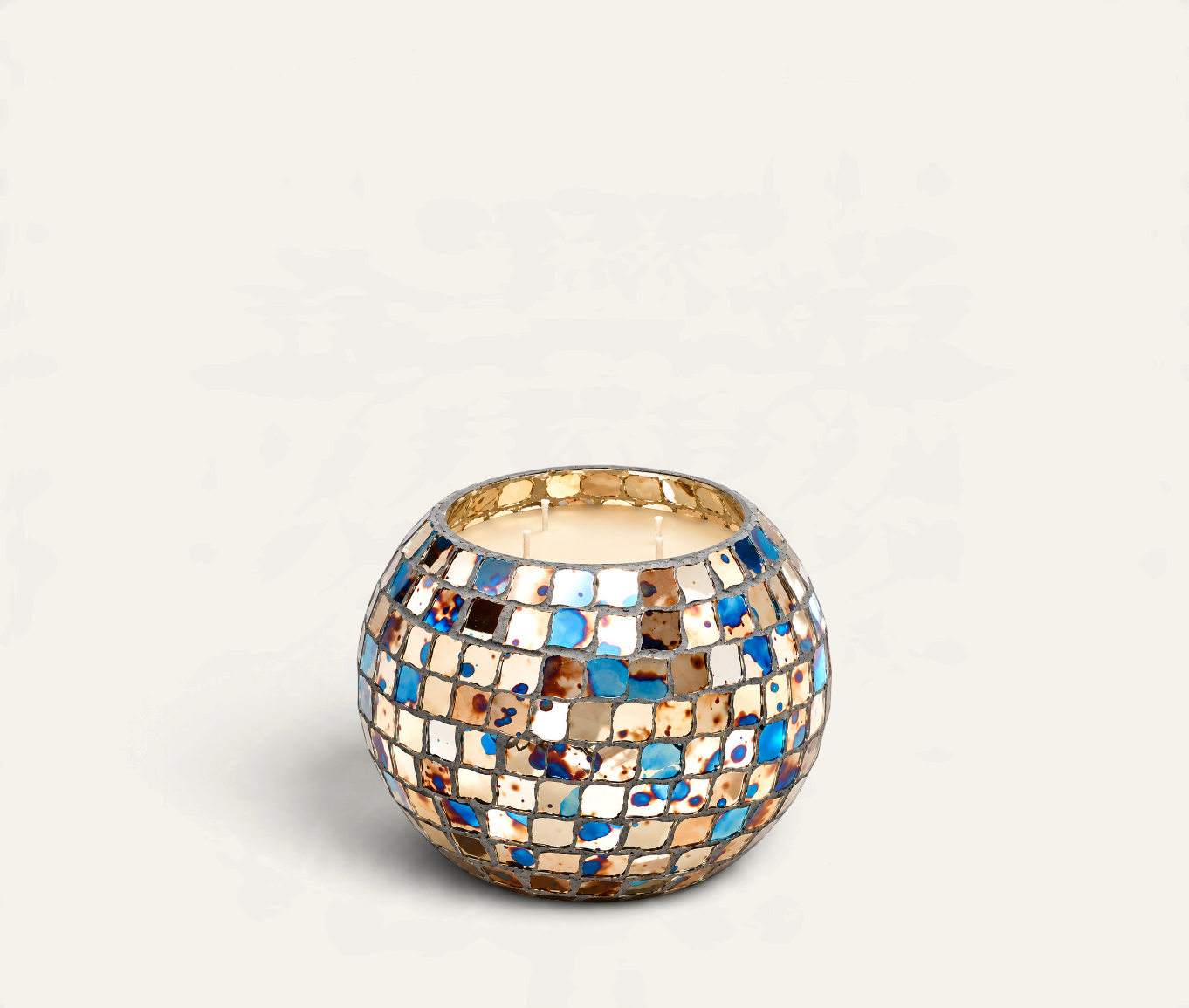 Vela aromática Hippie de THE IBIZA CANDLES en recipiente esférico de mosaico multicolor con tonos azules y dorados.