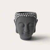 Vela artesanal Dark Moon de THE IBIZA CANDLES con forma de cabeza de Buda gris y detalles plateados