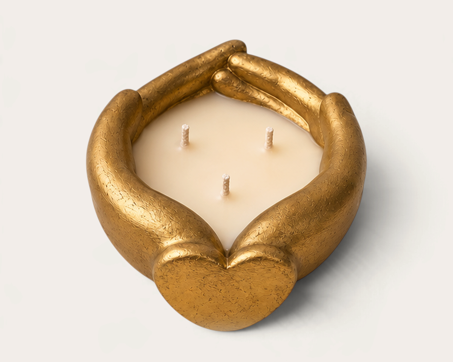 Vela artesanal THE IBIZA CANDLES con forma de manos doradas enlazadas en corazón, diseño escultórico de tres mechas.