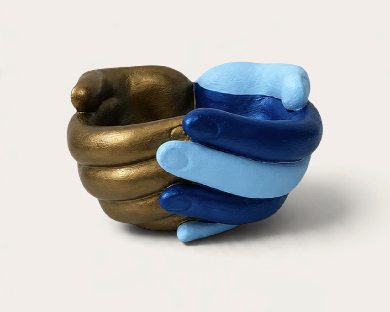 Vela escultórica Gold Mariner de THE IBIZA CANDLES con forma de manos entrelazadas en tonos dorado, azul y celeste.