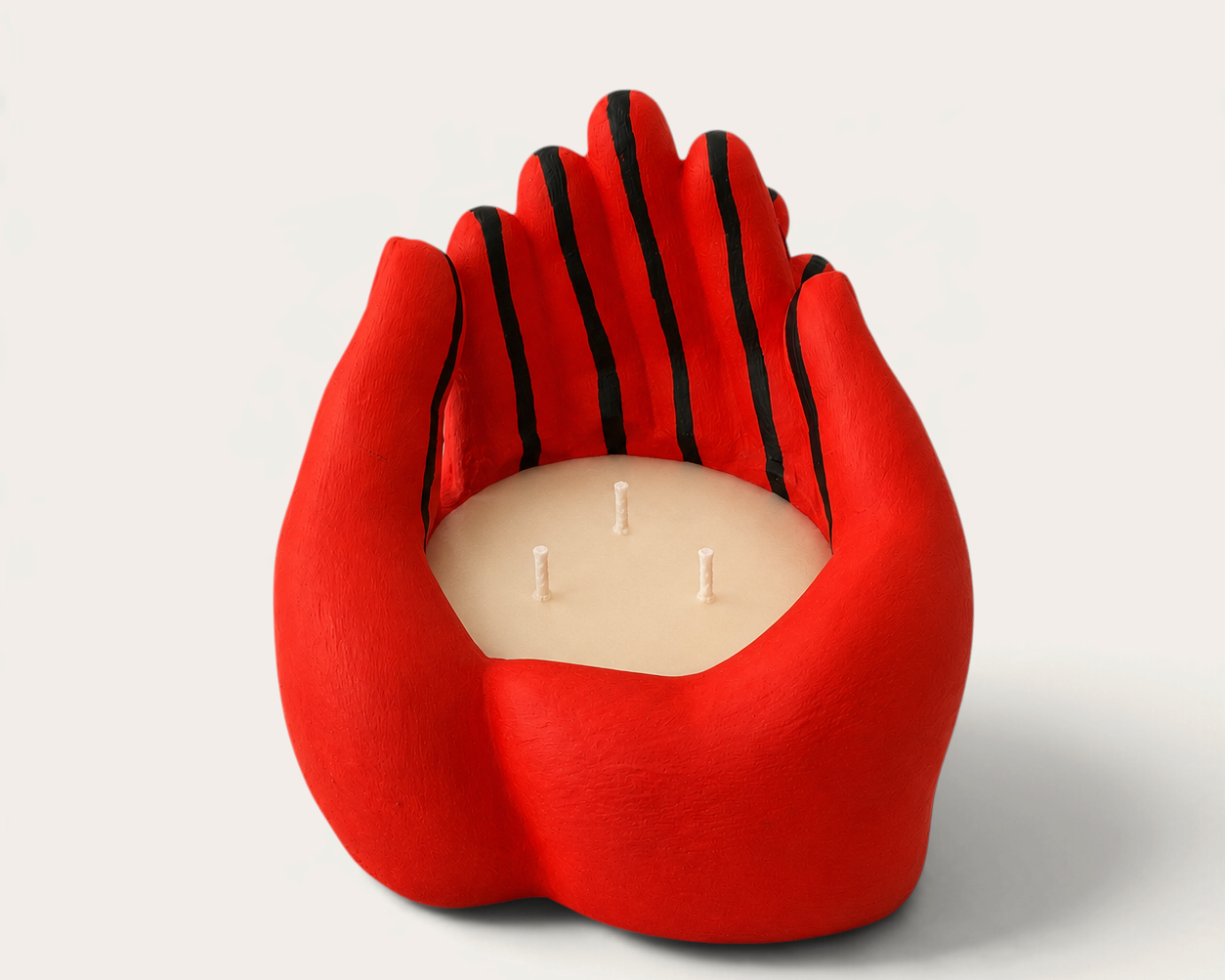 Vela artesanal THE IBIZA CANDLES con forma de manos rojas y rayas negras, pieza escultórica pintada a mano.