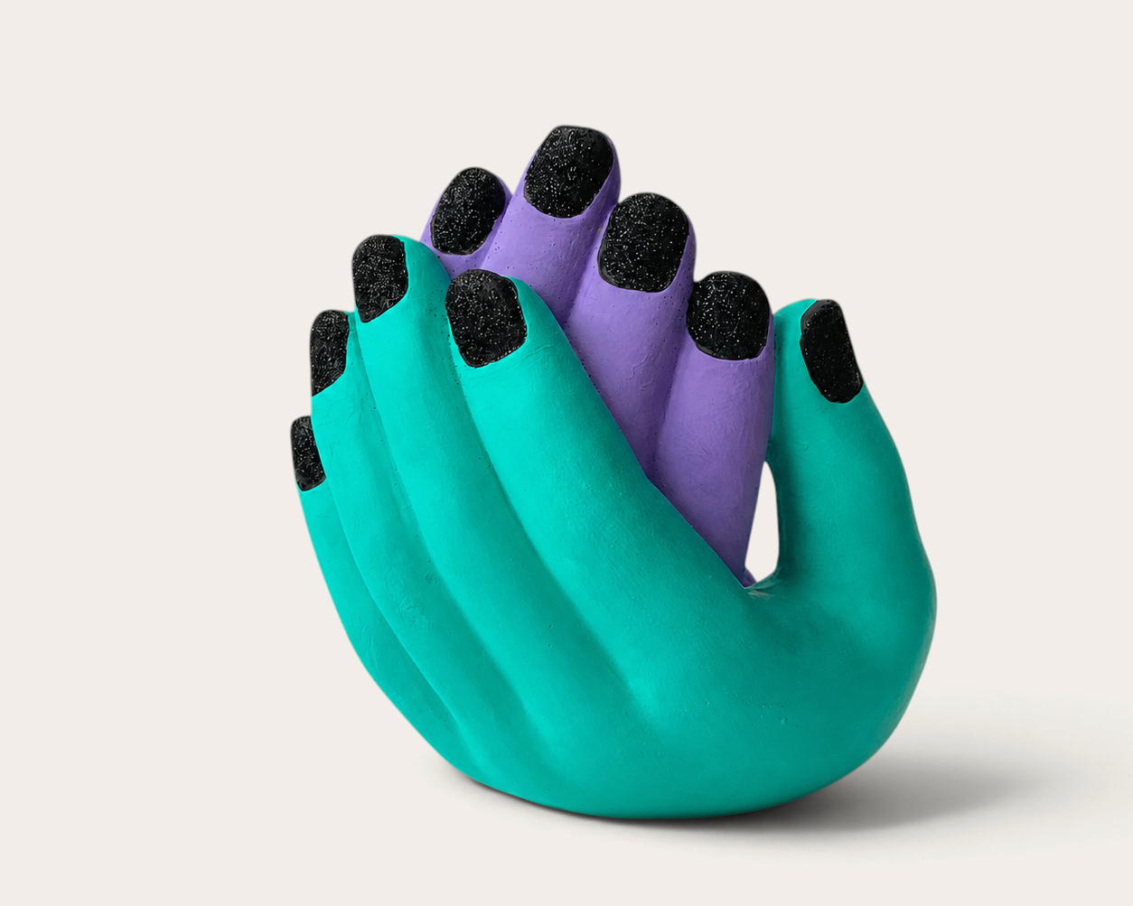 Vela escultórica THE IBIZA CANDLES con forma de manos entrelazadas en turquesa y morado con uñas negras brillantes.