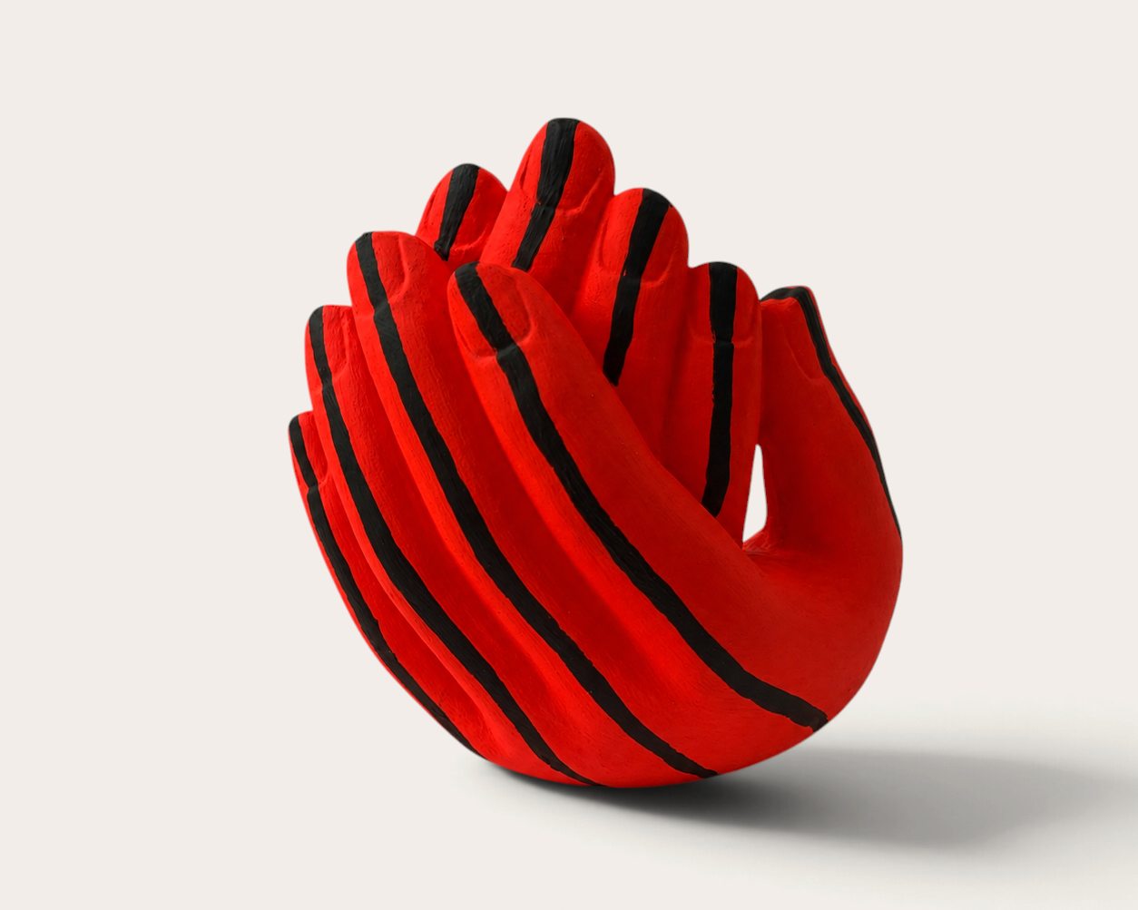 Vela escultórica Psichedelic Fluor de THE IBIZA CANDLES con forma de manos entrelazadas en rojo vibrante y rayas negras