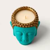 Vela artesanal THE IBIZA CANDLES con forma de cabeza de Buda en color turquesa y detalles dorados en el cabello.