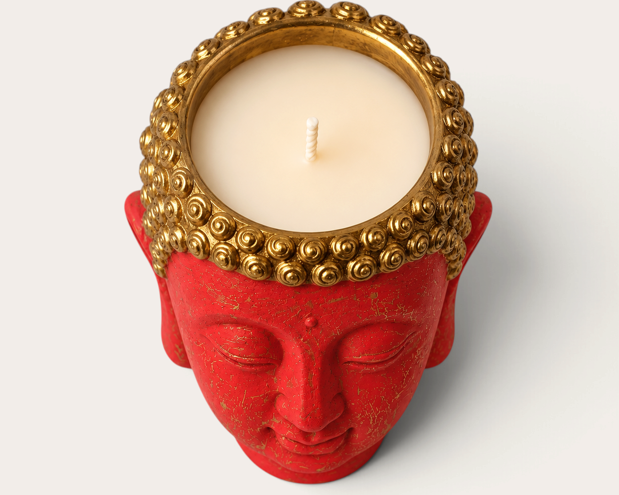 Vela artesanal THE IBIZA CANDLES con forma de cabeza de Buda roja y detalles dorados, vista cenital