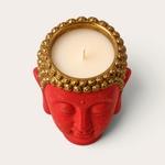Vela artesanal THE IBIZA CANDLES con forma de cabeza de Buda roja y detalles dorados, vista cenital