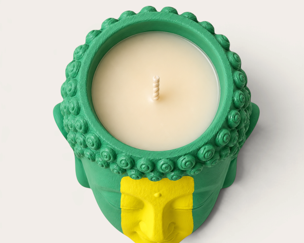 Vela artesanal Brazilian de THE IBIZA CANDLES con forma de cabeza de Buda en tonos verde y amarillo, vista cenital.