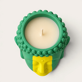 Vela artesanal Brazilian de THE IBIZA CANDLES con forma de cabeza de Buda en tonos verde y amarillo, vista cenital.