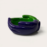 Vela escultórica artesanal THE IBIZA CANDLES con forma de manos entrelazadas en color morado y verde brillante.