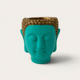 Vela escultórica THE IBIZA CANDLES con forma de cabeza de Buda en color turquesa y detalles dorados pintada a mano.