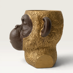 Vela decorativa THE IBIZA CANDLES con forma de cabeza de simio en tonos bronce y oro, diseño escultórico detallado