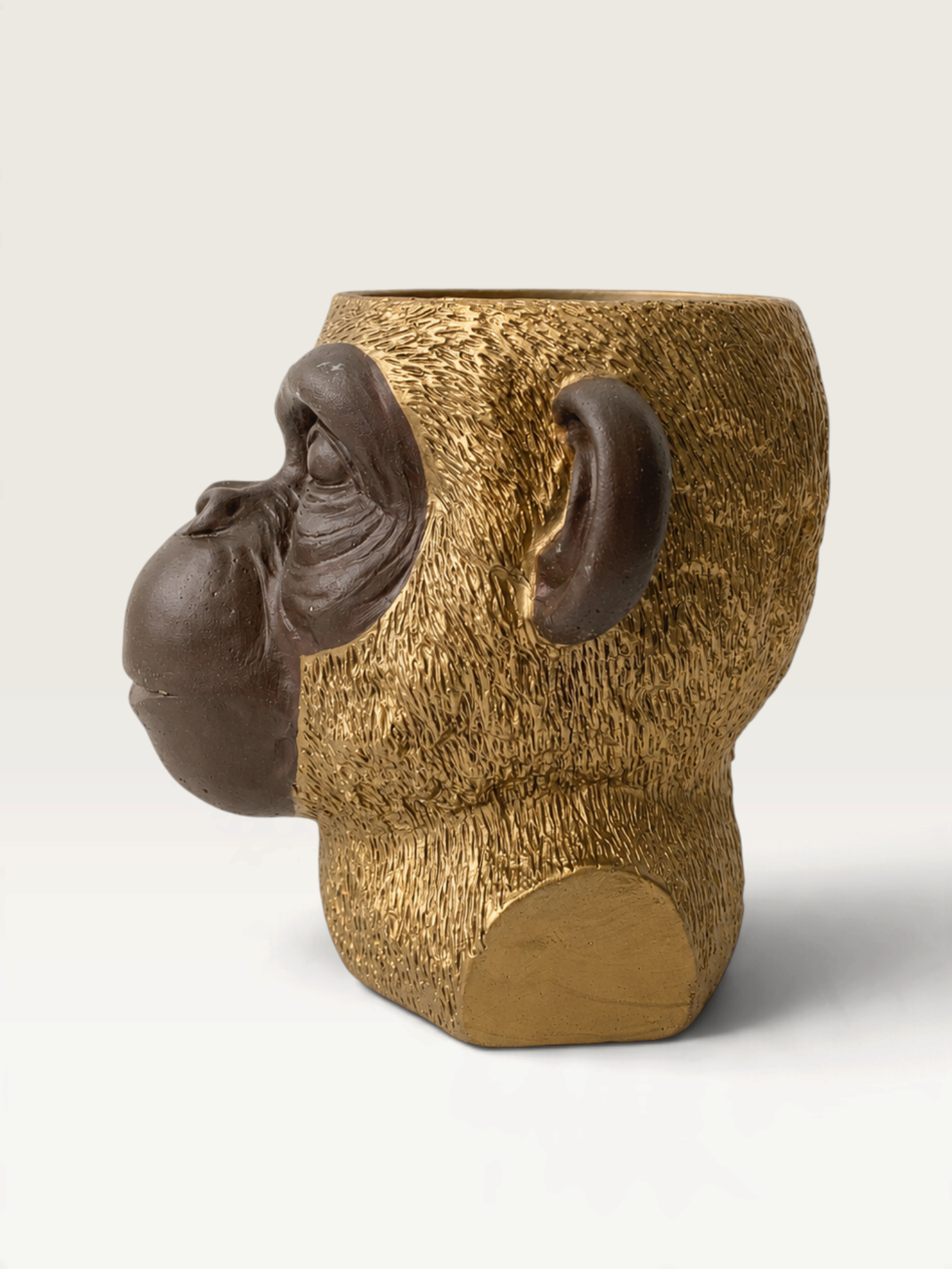 Vela decorativa THE IBIZA CANDLES con forma de cabeza de simio en tonos bronce y oro, diseño escultórico detallado